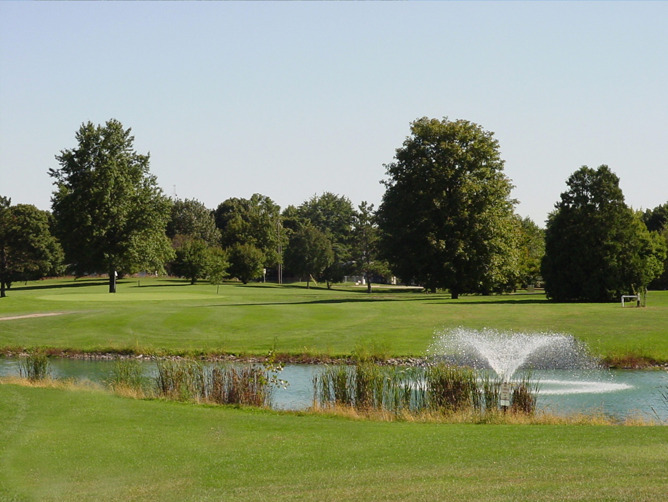 Lush green golf course with pond